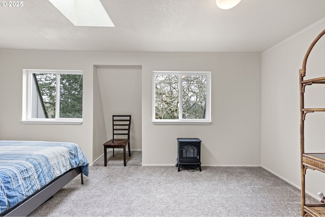 carpeted bedroom with ornamental molding, a textured ceiling, a skylight, baseboards, and a wood stove