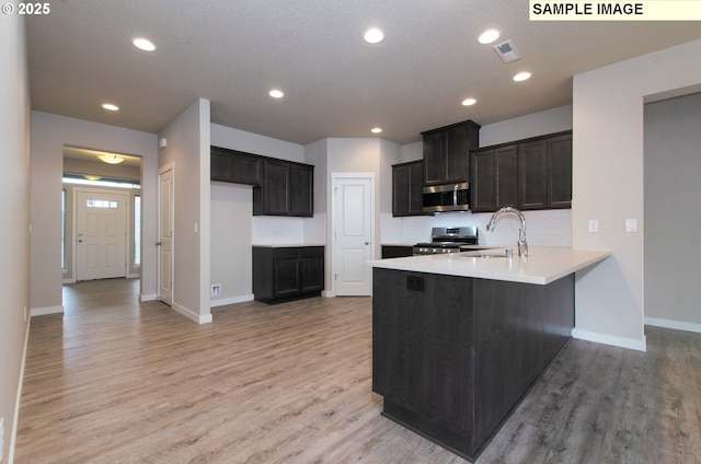 kitchen with stainless steel appliances, light hardwood / wood-style flooring, kitchen peninsula, and sink