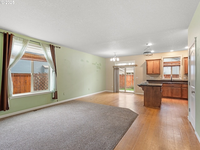 kitchen with dark countertops, a center island, open floor plan, light wood-type flooring, and an inviting chandelier