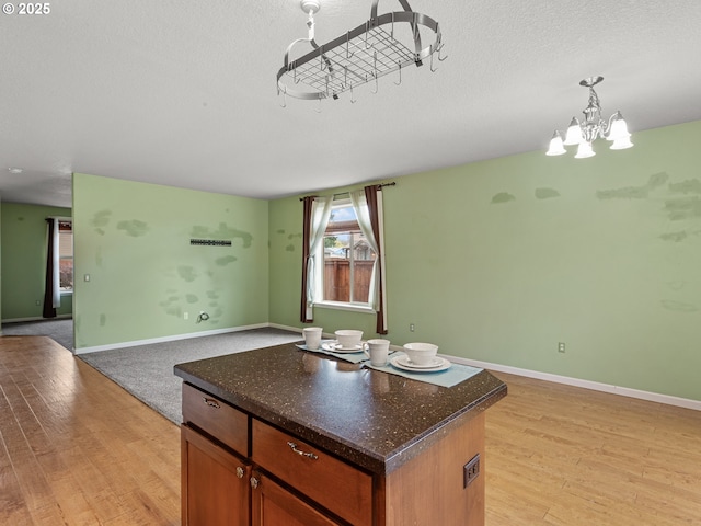 kitchen featuring light wood-style flooring, a notable chandelier, open floor plan, and a textured ceiling