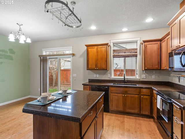 kitchen featuring a sink, light wood-style floors, black appliances, and a healthy amount of sunlight