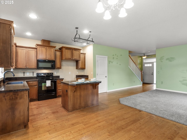 kitchen with brown cabinets, black appliances, a sink, a kitchen island, and dark countertops