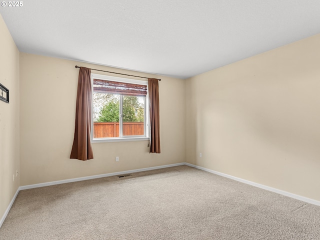 carpeted spare room featuring visible vents and baseboards