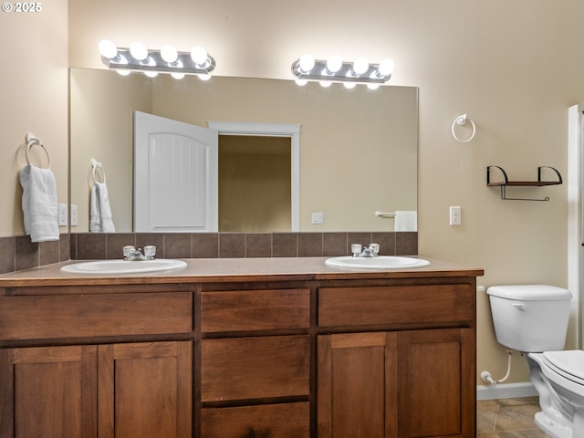 full bath featuring a sink, toilet, double vanity, and tile patterned floors