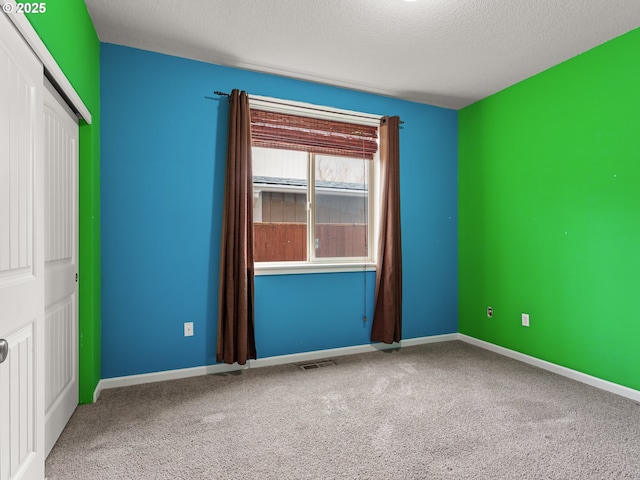 unfurnished bedroom featuring visible vents, baseboards, carpet floors, a closet, and a textured ceiling