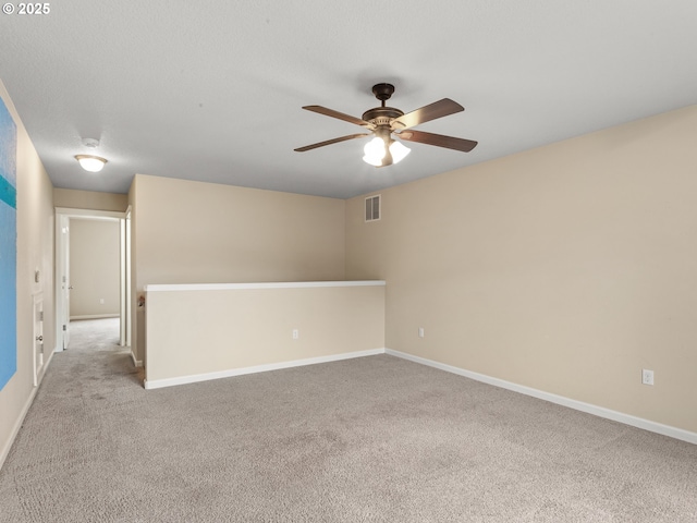 spare room featuring visible vents, light carpet, baseboards, and ceiling fan