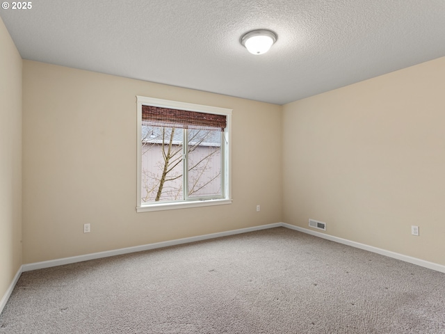 unfurnished room with visible vents, baseboards, a textured ceiling, and carpet flooring