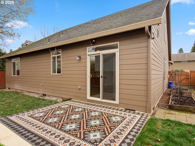 back of house featuring crawl space, a vegetable garden, and fence