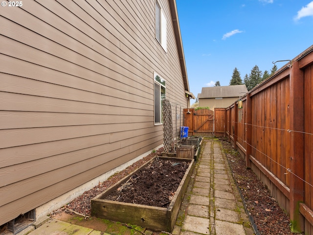 view of property exterior with a vegetable garden, a gate, and fence