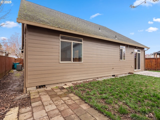 back of property featuring a shingled roof, a lawn, a fenced backyard, and a patio area