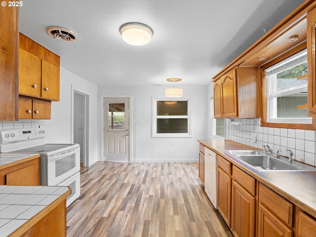2745 SW 187th Ave, Beaverton, OR 97003 - kitchen with white appliances, backsplash, light wood finished floors, brown cabinetry, and tile counters