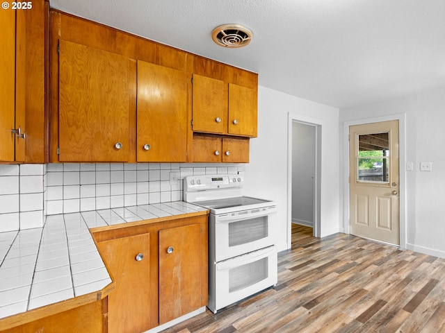 2745 SW 187th Ave, Beaverton, OR 97003 - kitchen with white range with electric cooktop, tile countertops, decorative backsplash, and brown cabinets