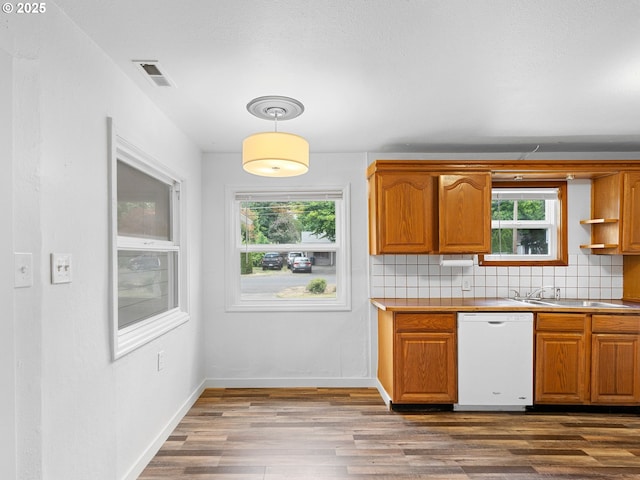 2745 SW 187th Ave, Beaverton, OR 97003 - kitchen with white dishwasher, dark wood finished floors, brown cabinets, backsplash, and pendant lighting