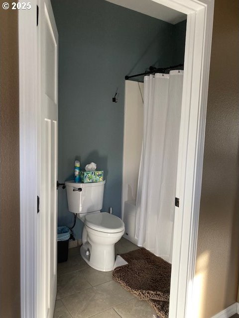 bathroom featuring tile patterned flooring, shower / bath combo, and toilet