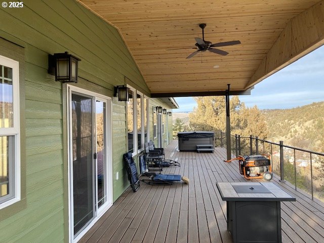 deck with ceiling fan, a mountain view, and a hot tub