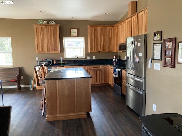 kitchen with sink, stainless steel appliances, dark hardwood / wood-style flooring, a kitchen bar, and a kitchen island