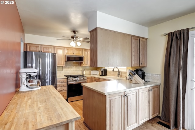 kitchen with a sink, appliances with stainless steel finishes, tasteful backsplash, and a peninsula