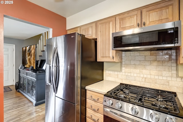 kitchen with appliances with stainless steel finishes, decorative backsplash, and light wood-type flooring