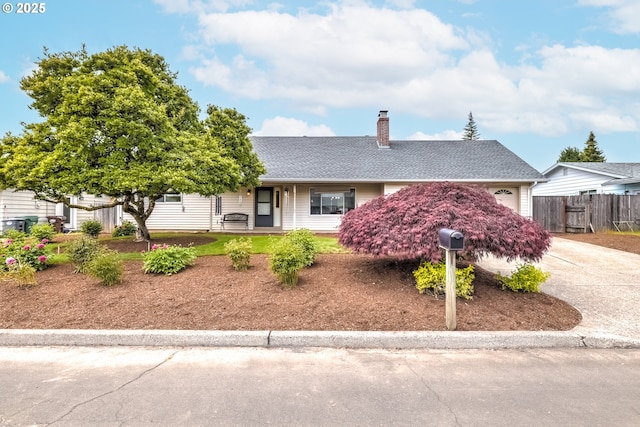 single story home featuring a chimney, a garage, fence, concrete driveway, and a shingled roof