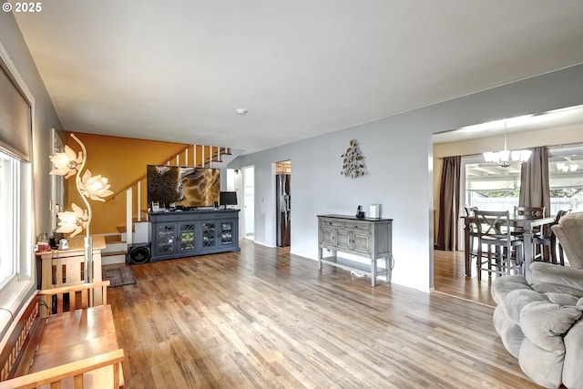 living room featuring an inviting chandelier, wood finished floors, and stairway