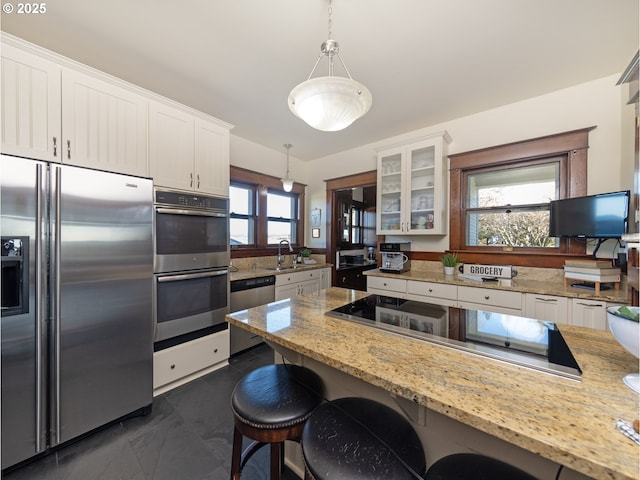 kitchen featuring stainless steel appliances, a breakfast bar, hanging light fixtures, and white cabinetry