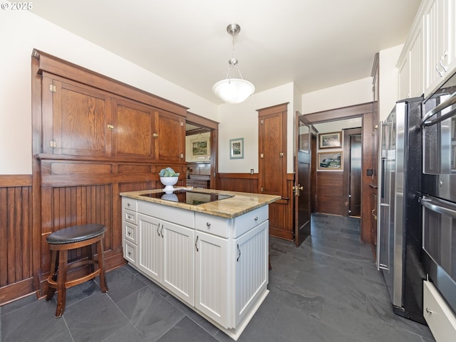 kitchen with decorative light fixtures, white cabinets, wood walls, and light stone counters