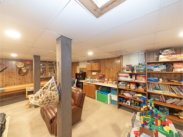 basement featuring light colored carpet and wooden walls