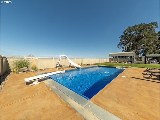 view of swimming pool with a patio area, a diving board, and a water slide