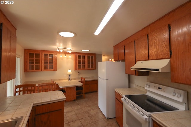 kitchen with white appliances, tile countertops, and sink