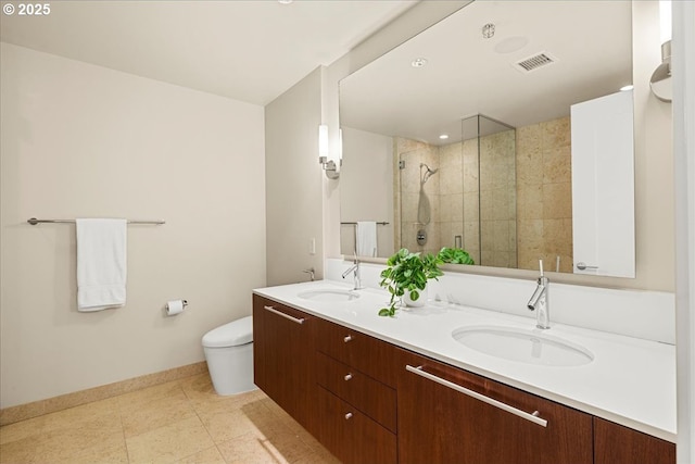 bathroom featuring a shower stall, baseboards, toilet, double vanity, and tile patterned floors