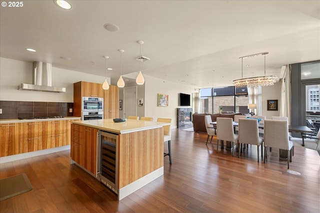 311 NW 12th Ave Unit 602, Portland, OR 97209 - kitchen featuring wall chimney exhaust hood, beverage cooler, modern cabinets, dark wood finished floors, and backsplash