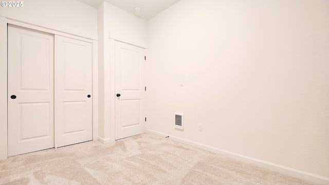 unfurnished bedroom featuring light colored carpet and a closet