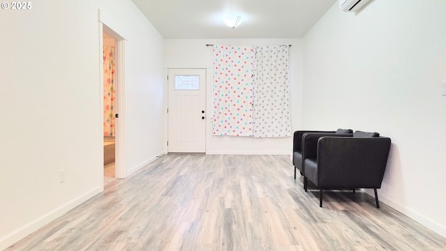 living area with light hardwood / wood-style floors and an AC wall unit