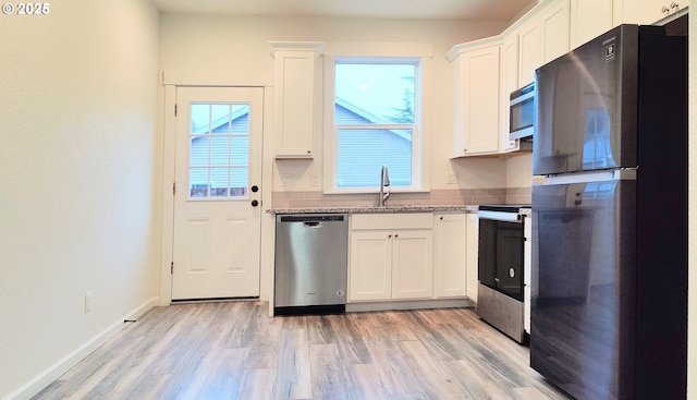 kitchen with sink, light hardwood / wood-style flooring, appliances with stainless steel finishes, light stone counters, and white cabinetry