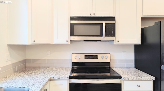 kitchen featuring light stone countertops, decorative backsplash, white cabinetry, and stainless steel appliances