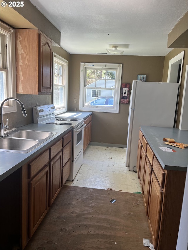 kitchen featuring a sink, dark countertops, and white appliances