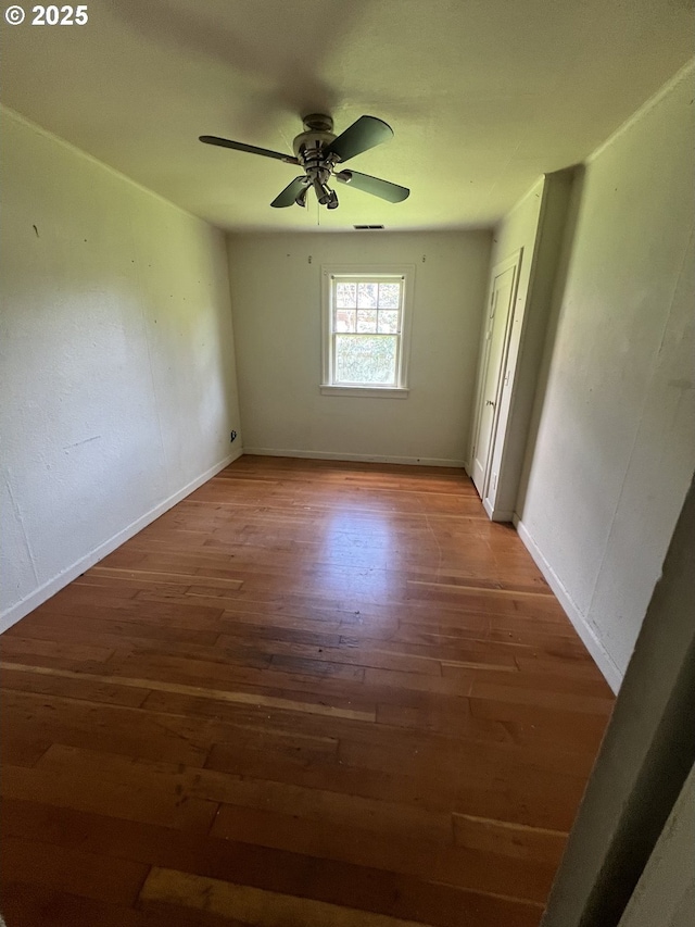 spare room with baseboards, ceiling fan, and wood finished floors