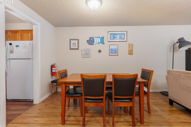 dining room with a textured ceiling and light wood-type flooring