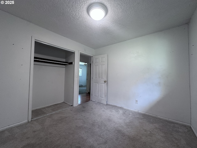 unfurnished bedroom with a closet, a textured ceiling, carpet floors, and baseboards