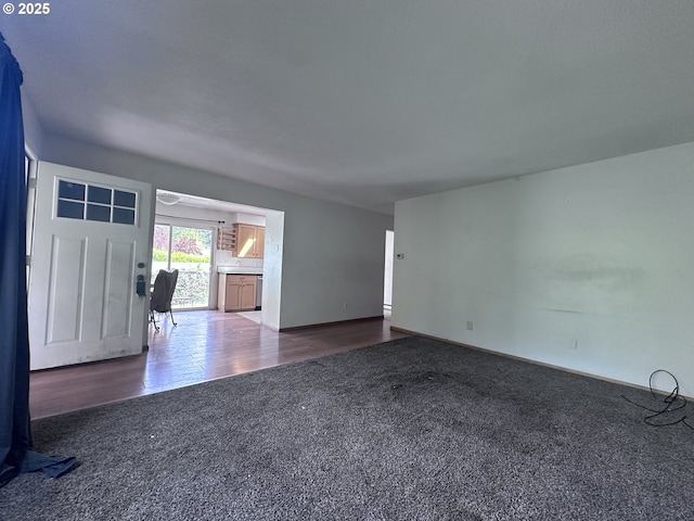 unfurnished living room featuring carpet floors and baseboards