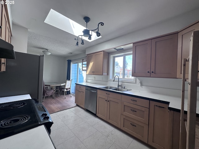 kitchen with a skylight, light countertops, stainless steel appliances, and a sink