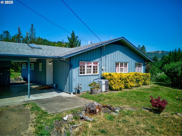 3034 Fisher Rd, Roseburg, OR 97471 - view of front of house with a carport, a front lawn, central air condition unit, a shingled roof, and board and batten siding