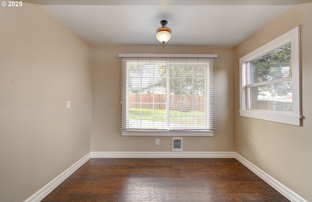 spare room with baseboards and dark wood-style flooring