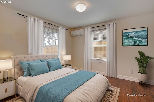 bedroom with baseboards, multiple windows, an AC wall unit, and wood finished floors