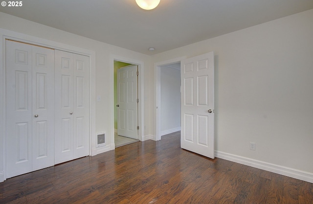 unfurnished bedroom featuring a closet, baseboards, visible vents, and dark wood-style flooring