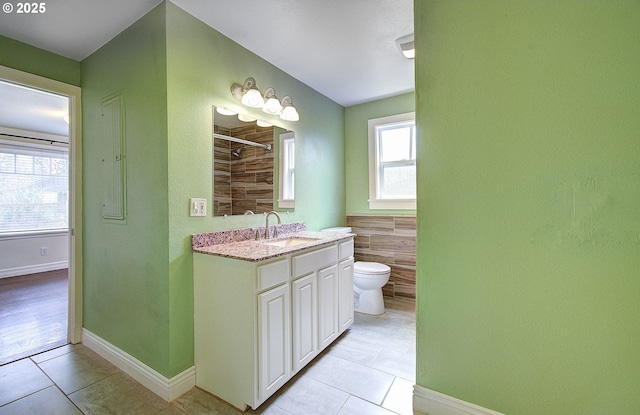 bathroom featuring vanity, a shower, tile walls, toilet, and tile patterned floors