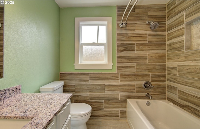 bathroom featuring toilet, vanity, shower / bathing tub combination, tile patterned floors, and tile walls