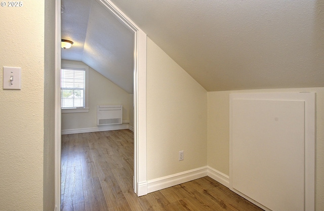 bonus room with baseboards, a textured ceiling, lofted ceiling, and wood finished floors