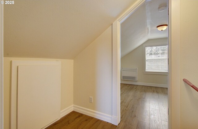 bonus room with baseboards, a textured ceiling, wood finished floors, and vaulted ceiling