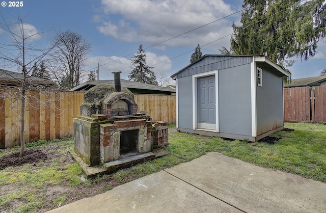 view of shed featuring a fenced backyard and an outdoor fireplace